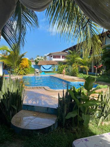 a swimming pool in a resort with a person in the background at Pousada Manga Azul in Barra de Camaratuba