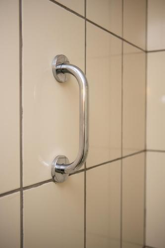 a shower door with a handle on a tiled wall at Hotel 10 Itajai/Navegantes in Itajaí