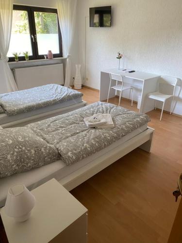 a bedroom with two beds and a table and a desk at Pension Platzhirsch Vogelsberg in Mücke
