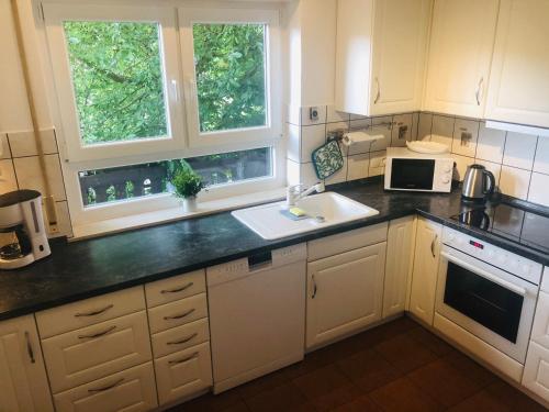 a kitchen with white cabinets and a sink and two windows at Pension Platzhirsch Vogelsberg in Mücke