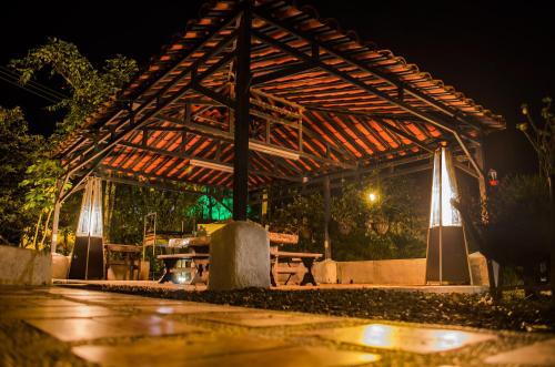 a wooden pergola with a picnic table under it at night at Finca Campestre La Adelita B&B in Salento