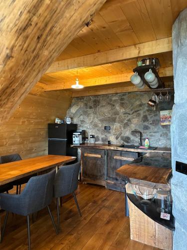 a kitchen with wooden tables and a stone wall at Cabana Balu in Măguri