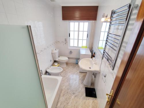 a white bathroom with two toilets and a sink at Airtegal Casa da Praia Cedeira in Cedeira