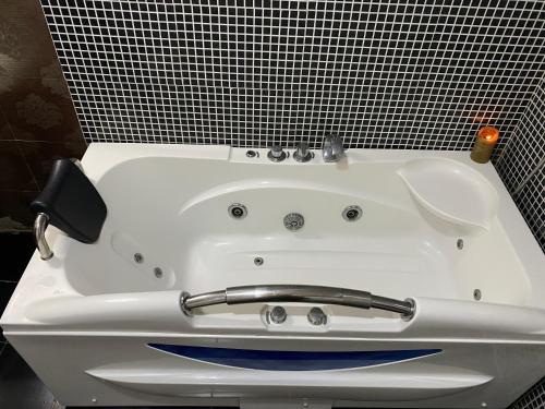 a white bath tub in a bathroom with black tiles at Oceanfront Executive Serviced Apartment Mbezi Beach in Dar es Salaam