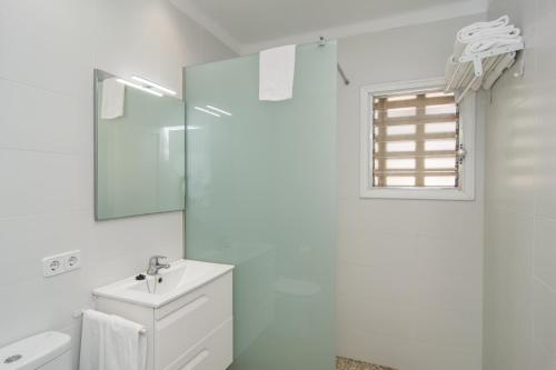 a white bathroom with a sink and a mirror at Villa Anglesos in Can Picafort