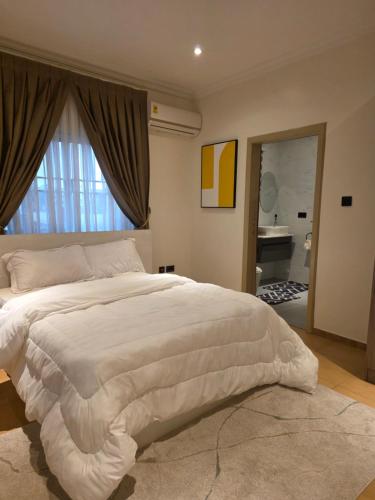 a bedroom with a large white bed and a bathroom at Terra Verte Court in Accra
