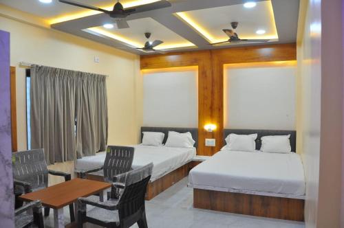 a hotel room with two beds and a table and chairs at Hotel Shivar in Kalam