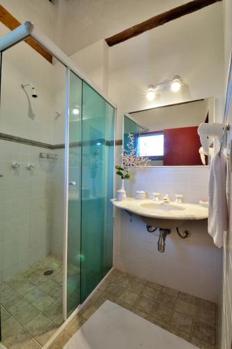 a bathroom with a shower and a sink and a mirror at Pousada Tiê Sahy in Barra do Sahy