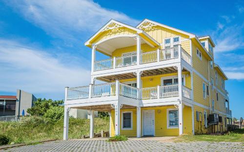 a yellow house with a balcony on top of it at Savannah - Nags Head MP 16, Oceanfront, Direct Beach Access, Pool, Hot Tub, Pool Table in Nags Head