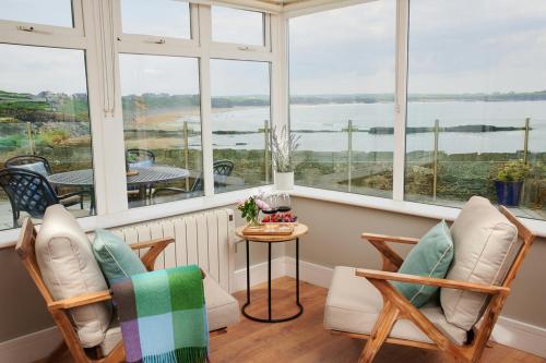 Una habitación con dos sillas y una mesa y ventanas. en Armada Cottages, en Spanish Point