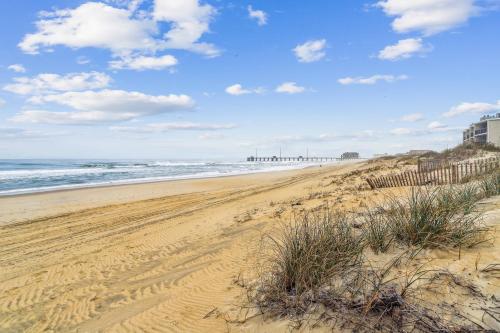 a sandy beach with a fence and the ocean at Hidden Treasure - Nags Head MP 16, Oceanfront, Private Beach Access, Pool, Hot Tub, Pool Table, Pets OK in Nags Head