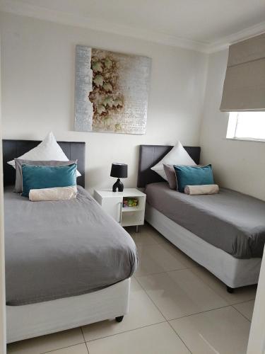 a bedroom with two beds with blue pillows at Stadium Apartment in Cape Town