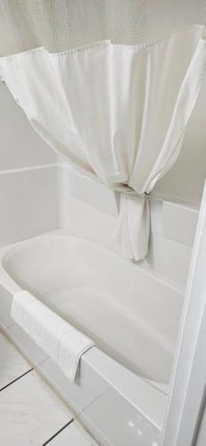 a white bath tub with a shower curtain on it at Rodeway Inn Roswell in Roswell