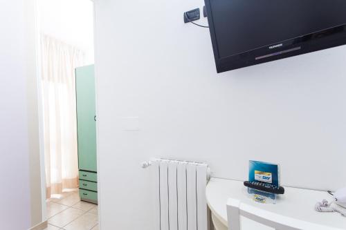 a bathroom with a tv on the wall above a sink at Hotel Flora in Milano Marittima