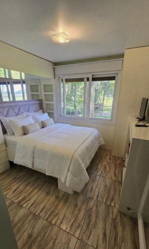 a bedroom with a large white bed and a window at Cabana da lagoa in Osório
