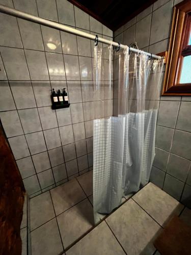a shower with white shower curtains in a bathroom at Cabaña kloski in Damita