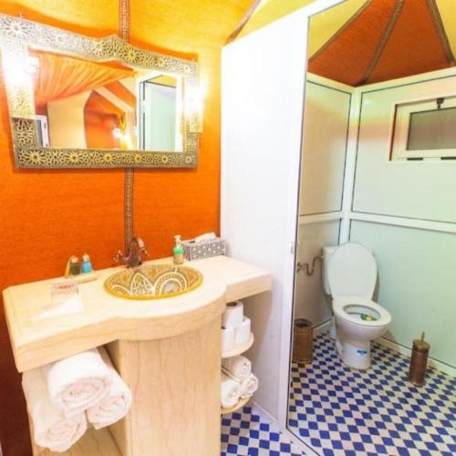 a bathroom with a sink and a toilet and a mirror at Luxury Desert Central Camp in Merzouga