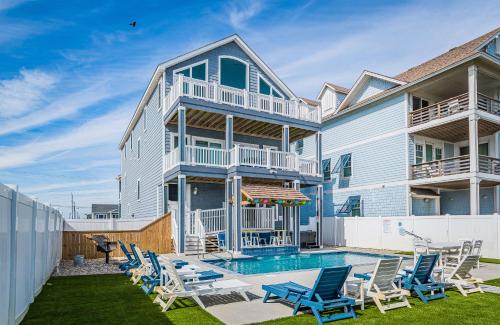 a house with a swimming pool and lounge chairs at Pier View Oasis - Nags Head MP 16, Oceanfront, Elevator, Theater, Pool, Hot Tub, Pets OK in Nags Head