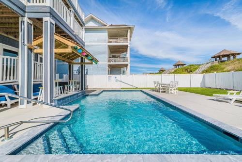 a swimming pool in the backyard of a home with a house at Pier View Oasis - Nags Head MP 16, Oceanfront, Elevator, Theater, Pool, Hot Tub, Pets OK in Nags Head