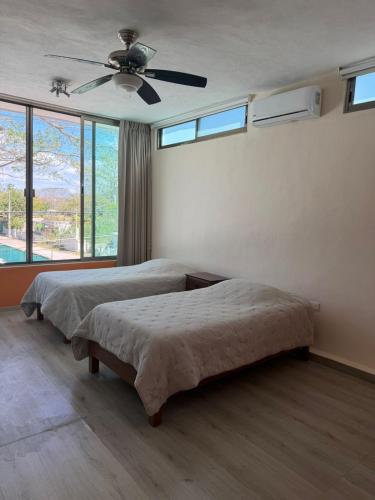 a bedroom with two beds and a ceiling fan at Casa Coco in Valladolid