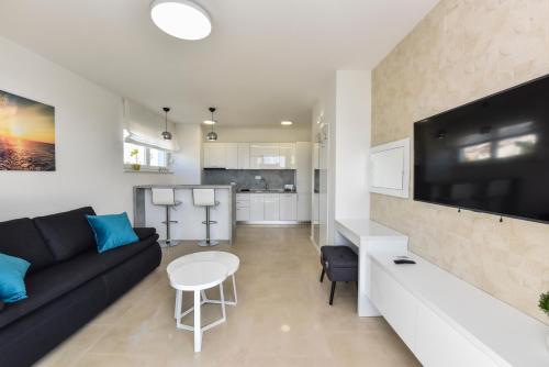 a living room with a black couch and a tv at Pool Apartments & Rooms Mare in Novalja