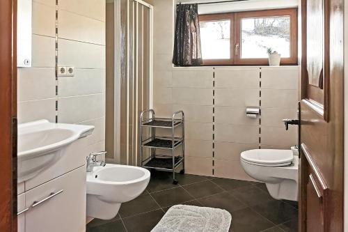 ein Badezimmer mit zwei Waschbecken, einer Toilette und einem Fenster in der Unterkunft Ferienwohnung Marienkäfer Rückzugsort inmitten der Natur mit Bergblick in Klobenstein