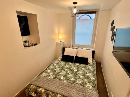 a small bed in a room with a window at Montbel'appart Studio Central tout équipé in Montbéliard