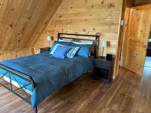 a bedroom with a bed and a wooden wall at Les Chalets du Lac Serein (Milot) in Saint Ludger de Milot