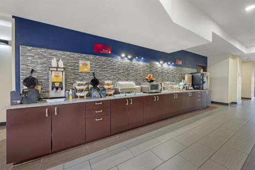 a large kitchen with brown cabinets and a brick wall at Best Western Plus Austin Airport Inn & Suites in Austin