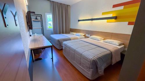 ein Hotelzimmer mit zwei Betten und einem Fernseher in der Unterkunft Hotel 10 Joinville in Joinville