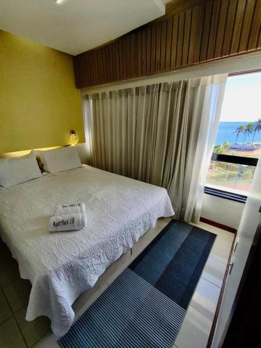 a bedroom with a bed with a view of the ocean at apart hotel 2 quartos frente mar in Salvador