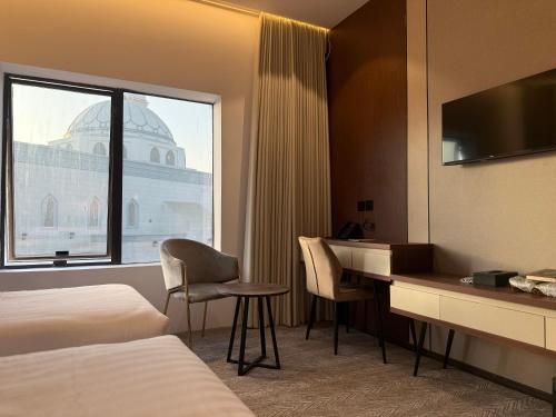 a hotel room with a desk and a window at Afaq Royal Almassar Hotel ex Hayah Al Iman in Mecca