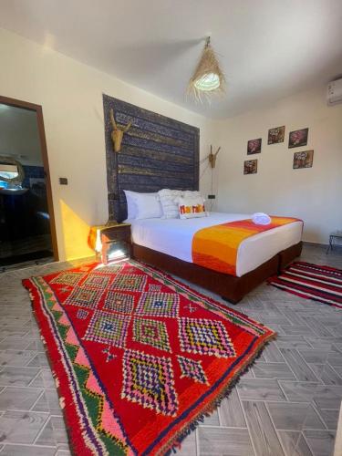 a bedroom with a bed with a red rug at Dar Benhoussa Imlil in Imlil