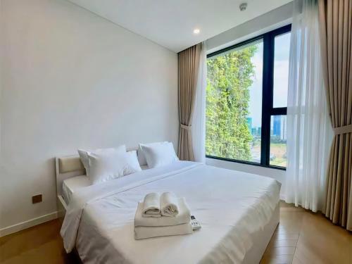 a bedroom with a white bed with a large window at Clasio - Lumiere Riverside in Ho Chi Minh City