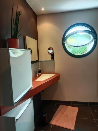 a bathroom with a sink and a mirror on the wall at L'Instant des Hôtes in Combrit