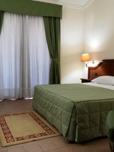 a bedroom with a bed with a green bedspread at Hotel Villa Peretti in Gela