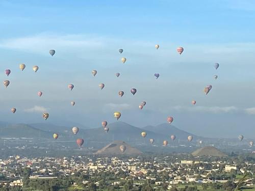 a bunch of hot air balloons flying in the sky at Complejo Turístico Mixcóatl in San Martín de las Pirámides