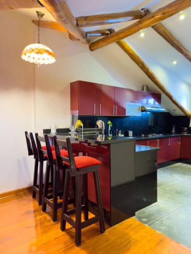 een keuken met rode kasten en een bar met barkrukken bij Illa Hotel in Cuzco