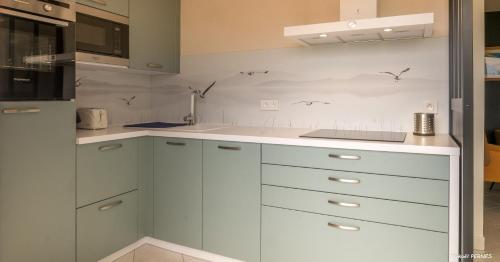 a white kitchen with white cabinets and a sink at REF 321 - LARMOR PLAGE appartement type 3 vue mer in Larmor-Plage