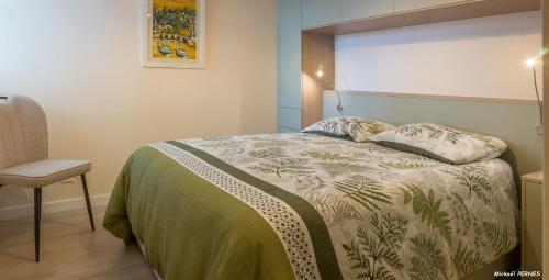 a bedroom with a bed and a chair at REF 321 - LARMOR PLAGE appartement type 3 vue mer in Larmor-Plage