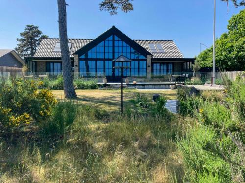 a house with glass windows and a tree at Beach Villa With Private Pier In Hou in Odder