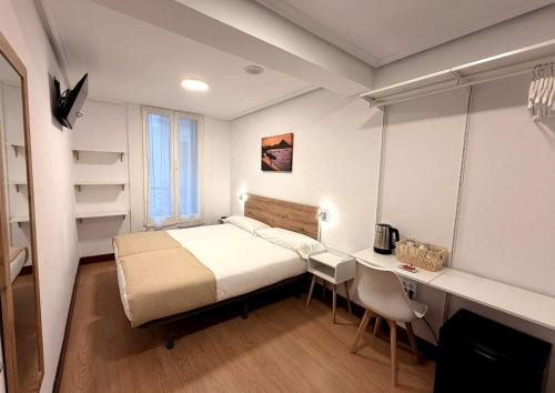a small bedroom with a bed and a desk at Pensión Santa Clara in San Sebastián