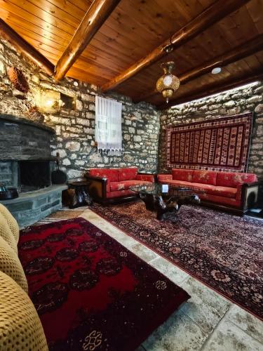 a living room with red couches and a fireplace at HerbStone Lodges in Asprangeloi