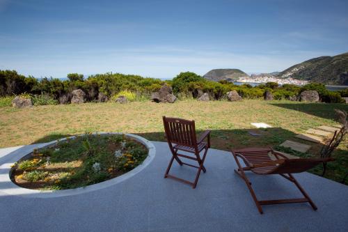 two chairs sitting on a patio with a garden at Cantinho das Buganvilias AT**** in Queimada