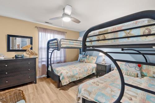 a bedroom with two bunk beds and a dresser at Sandpiper Cay 706 in Kitty Hawk