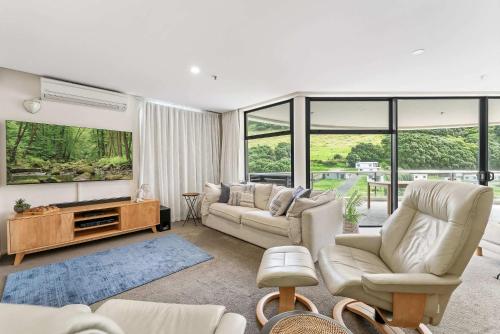 a living room with two couches and a tv at Oceanside Sunset Views in Mount Maunganui