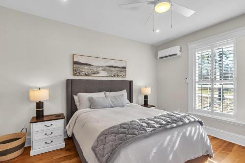 a white bedroom with a bed and two windows at The Park House in Batesville