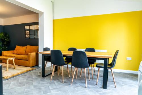 a dining room with a yellow wall and a table and chairs at 4 BD Sleeps 7 Parking WiFi in Coventry