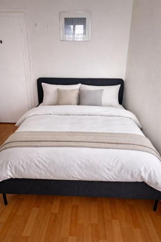 a large bed with white sheets and pillows at Central & cosy next to cathedral in Fribourg