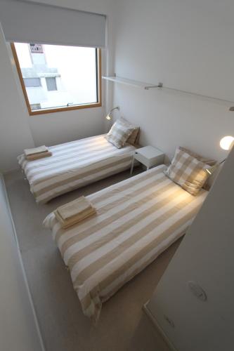 two beds in a room with a window at OPO.APT - Art Deco Apartments in Oporto's Center in Porto